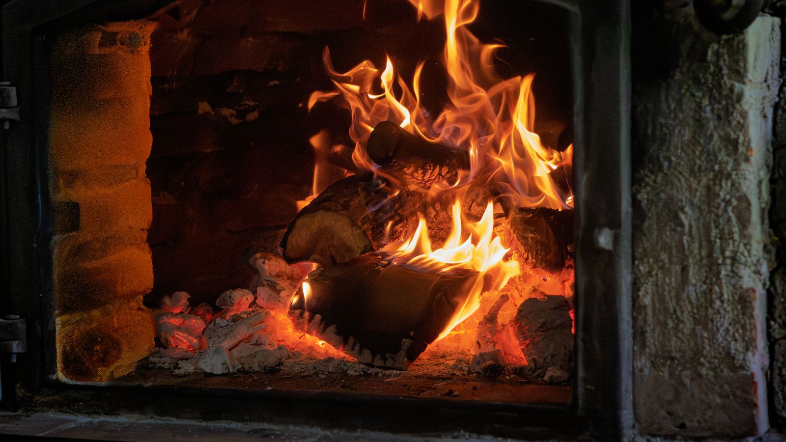 Le pizzaiolo enfourne une pizza dans le four à bois en pierre